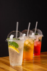 summer cool lemonades in plastic glasses with a plastic lid and straw. Berry strawberry, lemon and orange drinks. Summer mood. Quenching thirst in the heat. cafe drinks menu