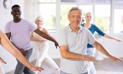 Active mature men and women practicing Hip-hop dance in training hall during dancing classes