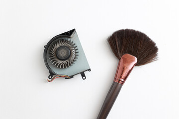 Cleaning brush and dusty laptop cooling fan on white background. Air vent fan for heatsink cooling...