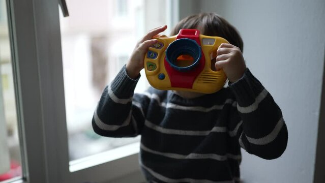 Child pretending to take photo with toy photography object in hand. Fun happy little boy playing at home with creative passtime