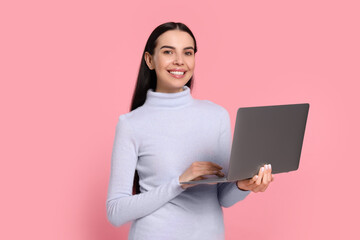 Happy woman with laptop on pink background