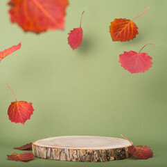 Wooden product display with flying red autumn leaves on green background. Fall mockup.
