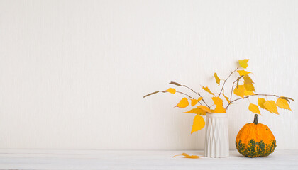 Thanksgiving background. Mockup with pumpkin yellow autumn leaves over white wall with copy-space.