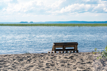 bench made of old pallets on a sandy shore of a vast lake