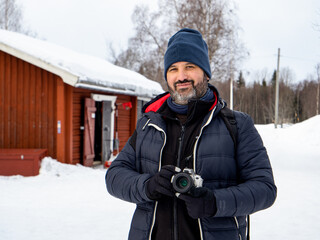 Fototapeta na wymiar Portrait of a male photographer looking at camera in a snowy landscape in a town in Sweden