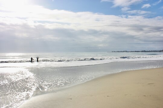 Distant silhouette of two people in the sea, Seacliff State Beach, Monterey Bay, Aptos, Santa Cruz, California, USA