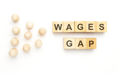 A picture of wooden block written wages gap with peg dolls on white background.