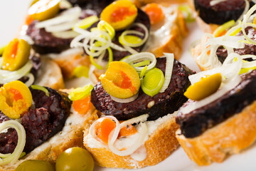 Image of tasty canapes from blood sausage with bread and olives, served at plate