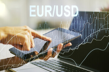 Creative EURO USD financial graph illustration and finger presses on a digital tablet on background, forex and currency concept. Multiexposure