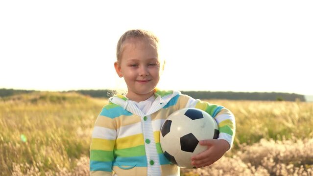 young girl happily playing football. green field. portrait capturing smiling face. she child filled ambition dreams becoming successful athlete sunset. envisions herself sportsman wearing uniform
