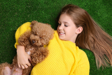 Little child with cute puppy on green grass, top view. Lovely pet