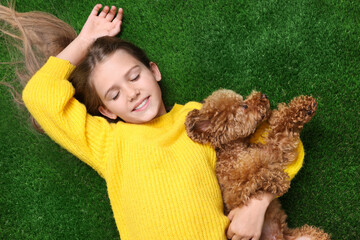 Little child with cute puppy on green grass, top view. Lovely pet