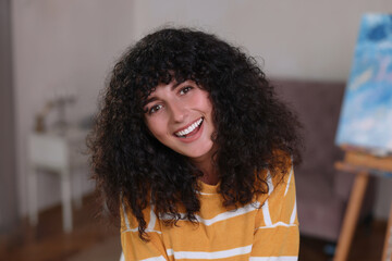 Fototapeta na wymiar Portrait of happy young woman in stylish sweater indoors