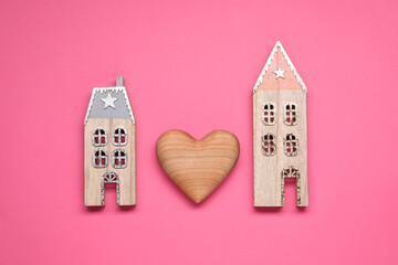 Long-distance relationship concept. Decorative heart between two house models on pink background,...