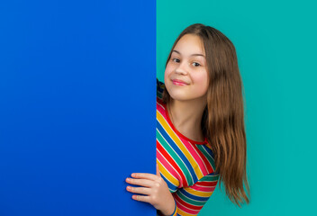 smiling girl behind blank blue paper with copy space for advertisement
