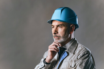 Portrait of a thoughtful elderly Caucasian worker in work clothes.