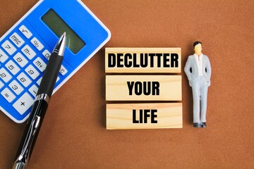 miniature people, calculator, pen and stick with the words Declutter Your Life