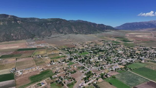 Aerial agriculture farm town mountain valley circle. Farming community agricultural economy. Spring summer weather mountain valley green agriculture field. Homes, barns and buildings.