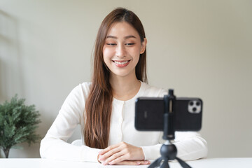 Young asian woman recording herself interview video via smartphone for her vlog.