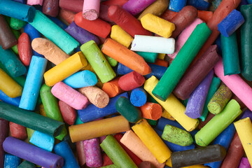 pile of multicolor used oil pastel crayons, close-up of old half used wax crayon pieces in full frame background, taken straight from above