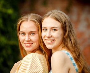 Obraz premium Young female friends outdoors in the city. They are sitting while talking at sunset in summer