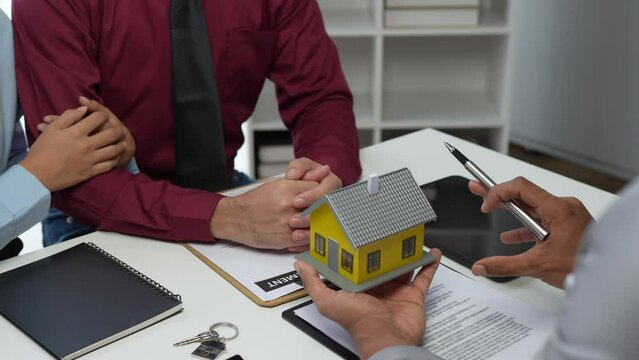 Real estate agent or sales manager is handing over a mockup house after offering terms and signing a home purchase contract and free home insurance, finance and after sales service concept.