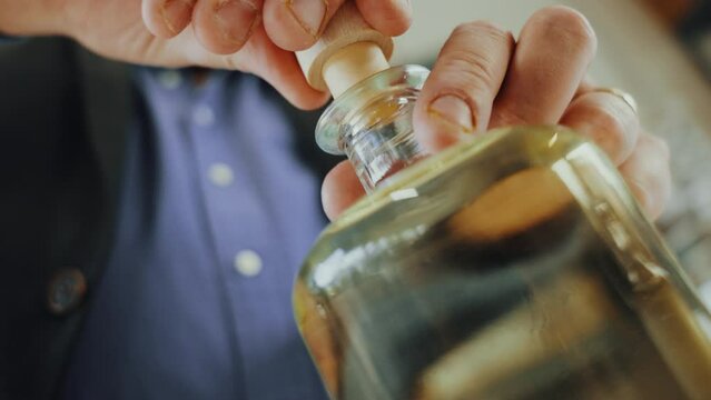 Close up shot of a male expert putting a cap on a glass bottle of distilled gin, quality control process in a gin distillery production