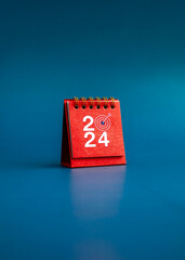 Happy new year 2024 vertical background. 2024 numbers year with target dart icon on red small desk...