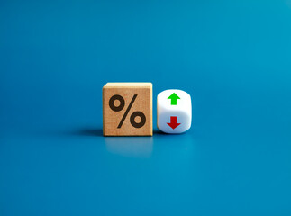 Fototapeta Percentage icon on wooden cube block and up and down arrow symbol on flipping white dice on blue background. Interest rate, financial stocks, ranking, GDP percent change, money exchange concepts. obraz