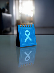 Cancer day concept. Ribbon icon on blue desk calendar cover on glass table. Cancer campaign calendar reminder appointment. Cancer Awareness month.