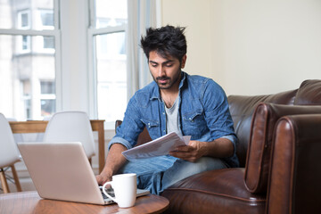 Asian man at home using a laptop.