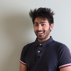 Asian man standing against green wall.