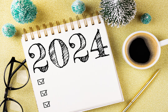 New year resolutions 2024 on desk. 2024 resolutions list with notebook, coffee cup, decorations on table. Goals, resolutions, plan, action concept. New Year 2024 template. Copy space
