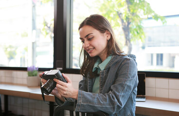 Obraz premium Beautiful woman is a professional photographer with a camera in a cafe using a computer.