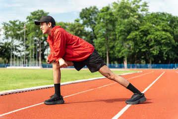 Obraz premium Medium shot, Young Asian man stretching his leg warm up before workout outdoor running track background. The man in sportswear exercises outside in the morning for health and wellbeing.