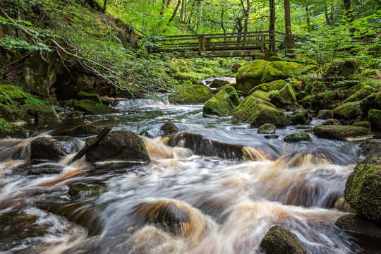 Wooden footbridge over Burbage Brook in the wonderful Padley Gorge near Grindleford, Peak District National Park, Derbyshire.