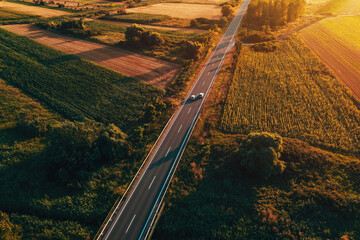Aerial shot of traffic on countryside road in summer sunset, high angle view drone pov image of...