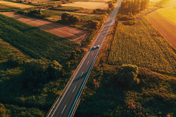 Aerial shot of traffic on countryside road in summer sunset, high angle view drone pov image of cars driving along the highway through Vojvodina