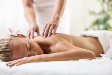 Obraz na płótnie Canvas Beatiful woman is enjoying relaxing back massage in cosmetology spa centre