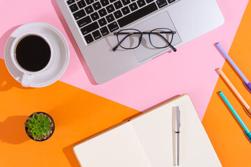 Trendy home office workspace with a cup of coffee, a laptop, some pens, a notebook, a pair of...