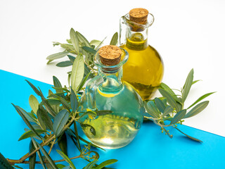 Olive concept, extra virgin olive oil flasks with olive tree leaves on a blue and white background