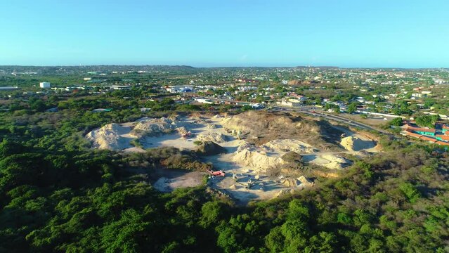 Drone establishing view of sandy loam fill site with excavator and heavy machinery