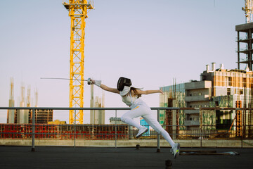 Two fencers woman practice on a rooftop with the city in the background.
