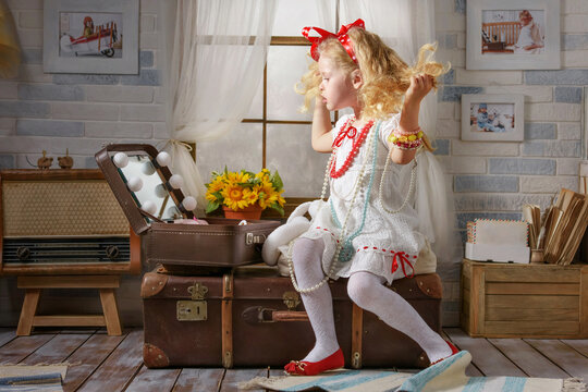 Little cute girl is playing with her toys in the attic room. Child imagines himself a princess and dreams of traveling...