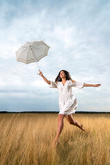 Young woman with a dress jumps childishly with an umbrella