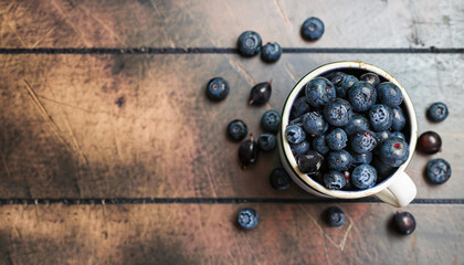 Organic fresh dark berries in vintage mug over rustic background with space for text, top view. Agriculture, Gardening, Harvest Concept.