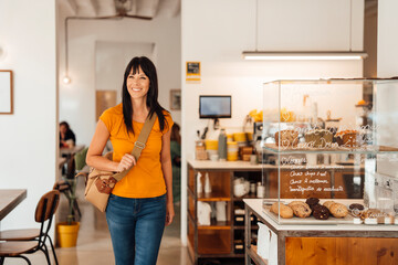 Happy woman walking with shoulder bag in cafe