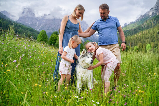 Father and mother looking at daughters playing with dog on grass