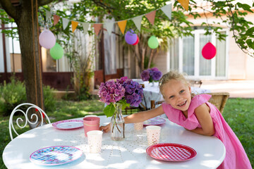 Smiling girl setting table for birthday event in garden