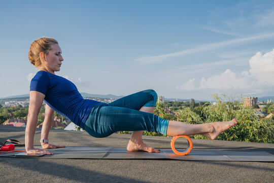 Blond woman exercising with foam roller on rooftop
